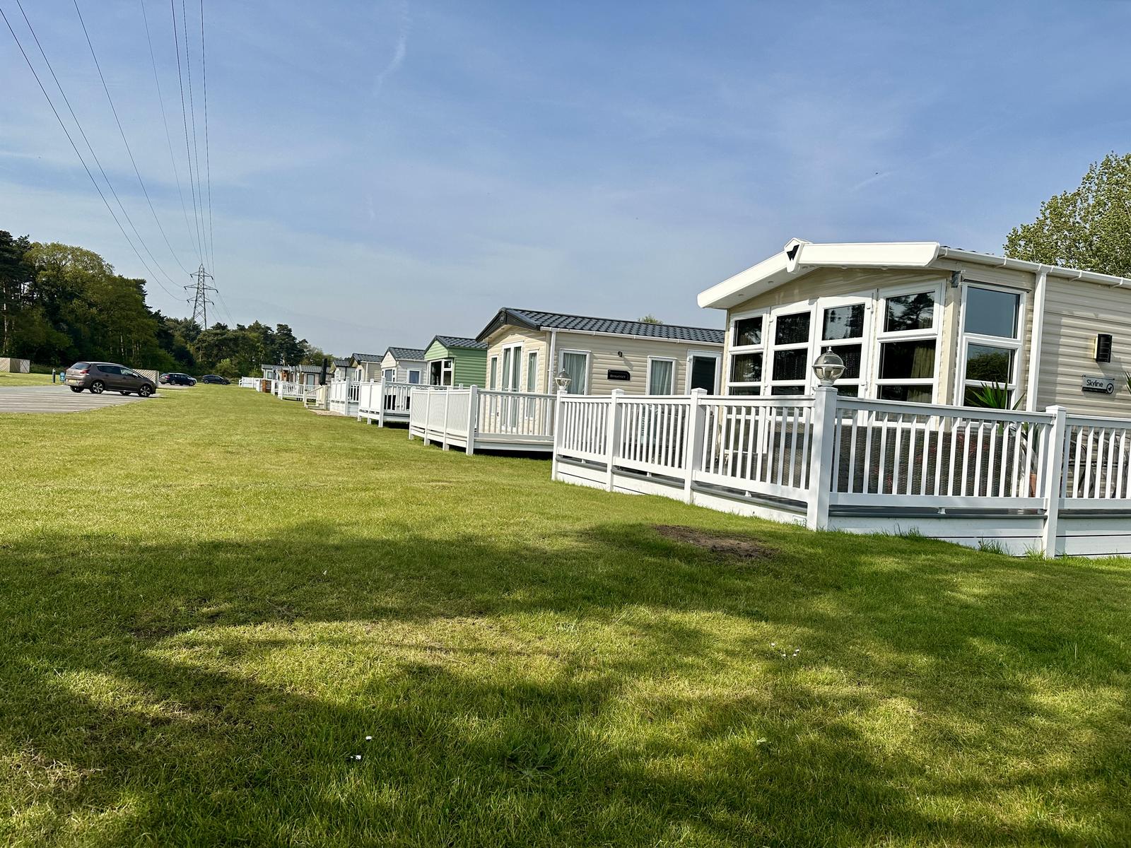 A row of modern static caravans with white decking on a sunny UK holiday park